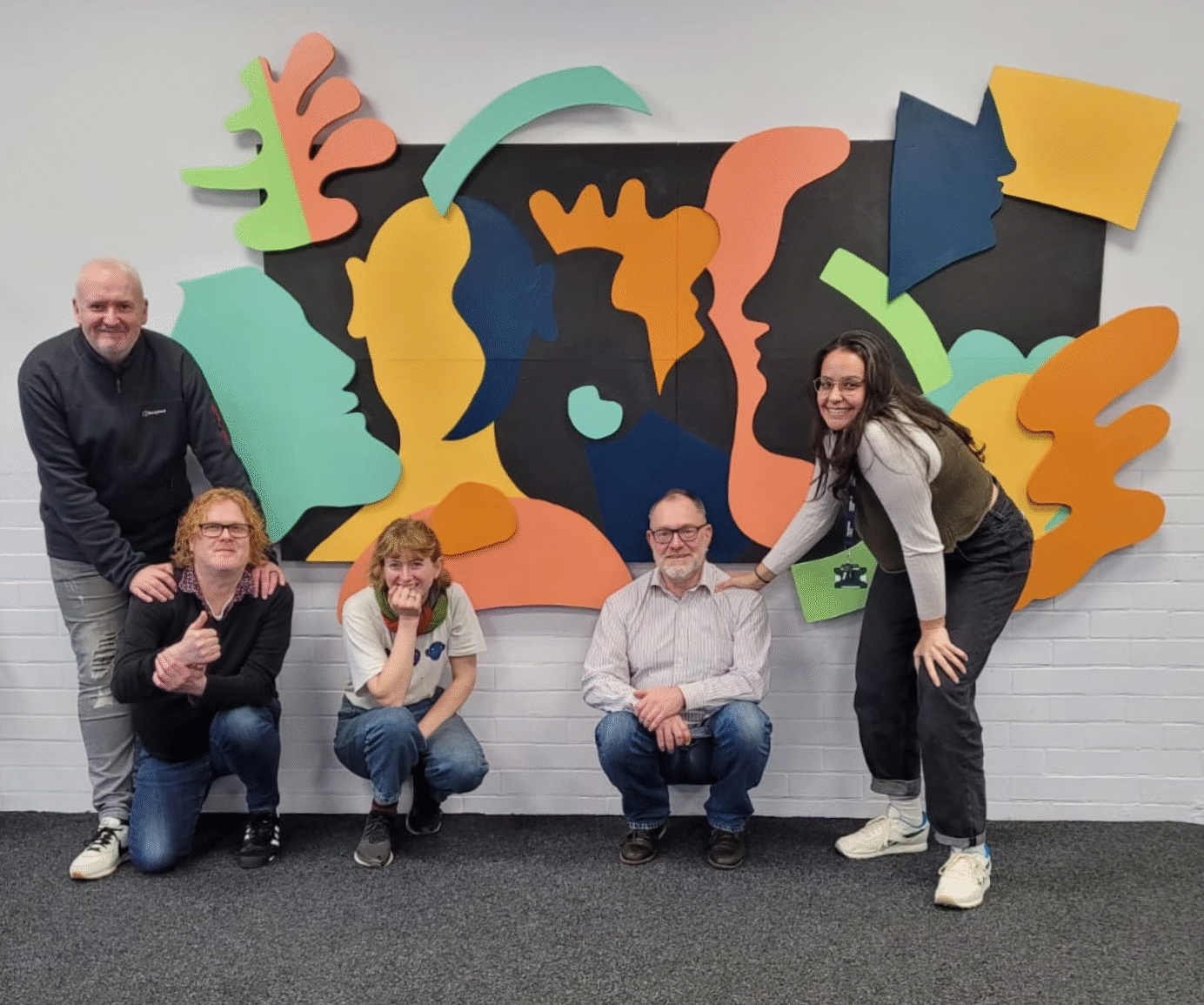 A photo of 5 people - part of the York MCN project - in the nursery room at York CVS with a collage in the background.